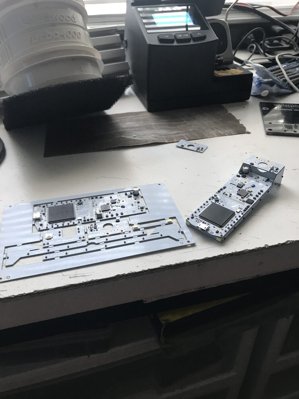 Assembled badge boards on a workbench next to soldering equipment